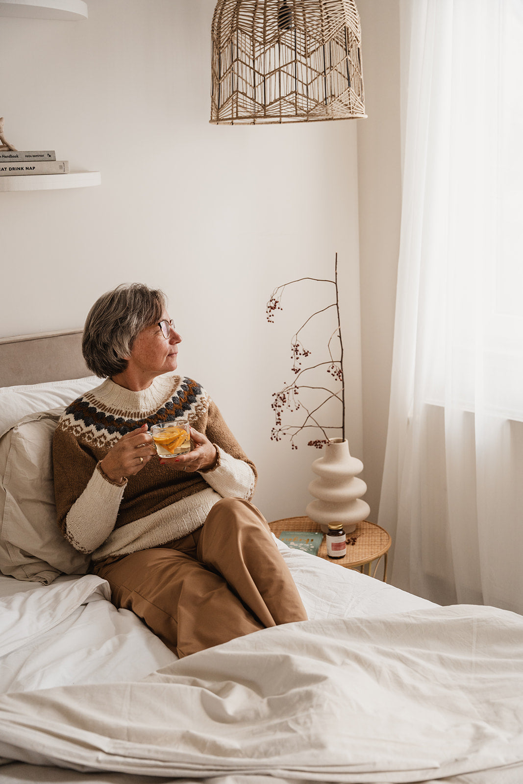 Oestrogeen tekort is vaak de oorzaak van overgangsklachten - een oudere vrouw zit met een kopje thee op bed.