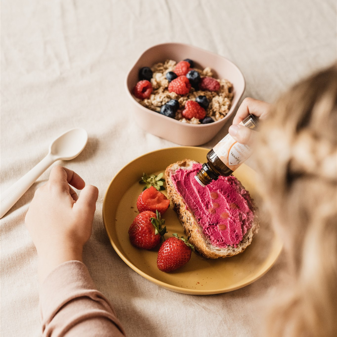 Sfeerfoto van de multivitamine druppels die op een broodje met groentespread worden gedruppeld.