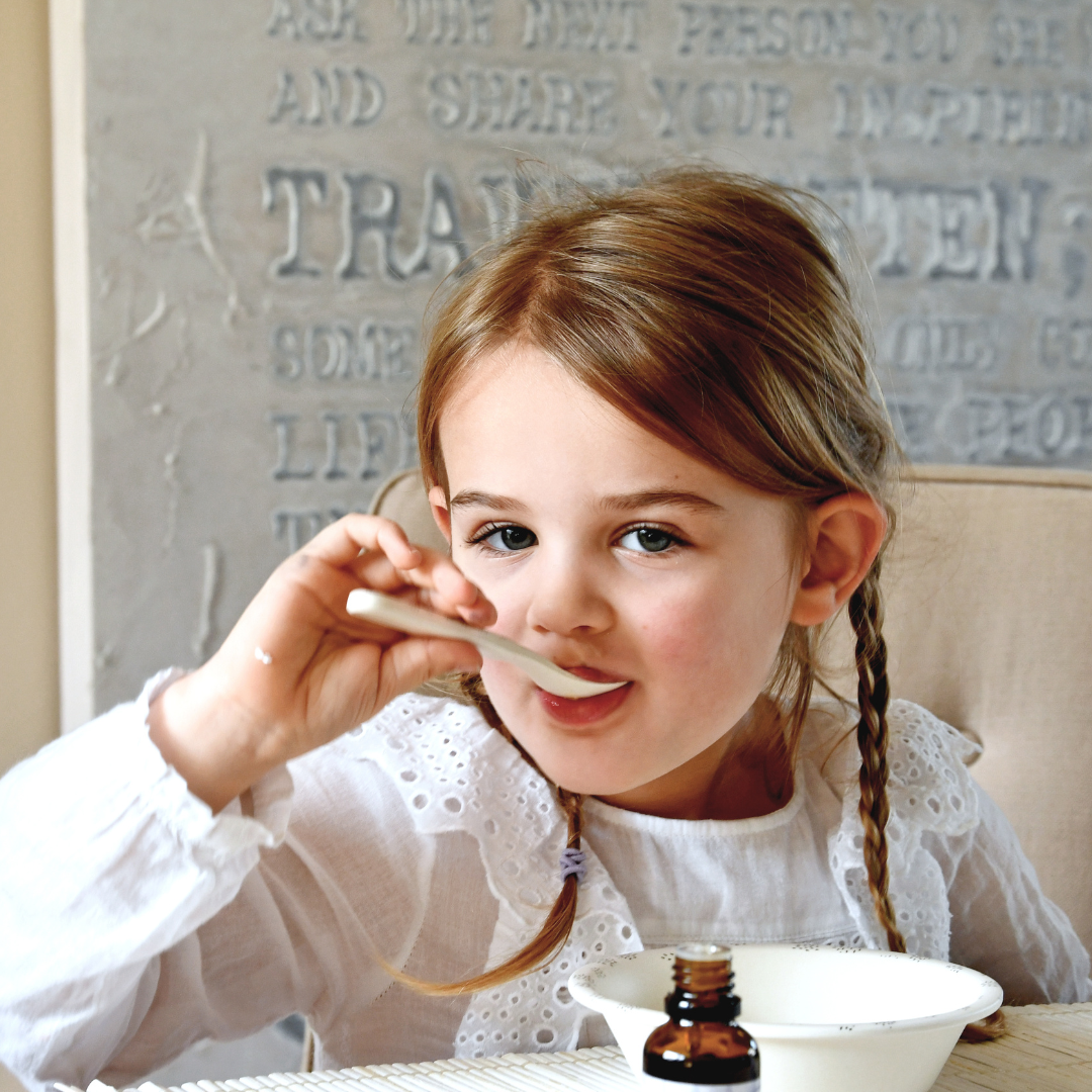 Sfeerfoto van de druppels, een kindje neemt een lepeltje met de druppels.