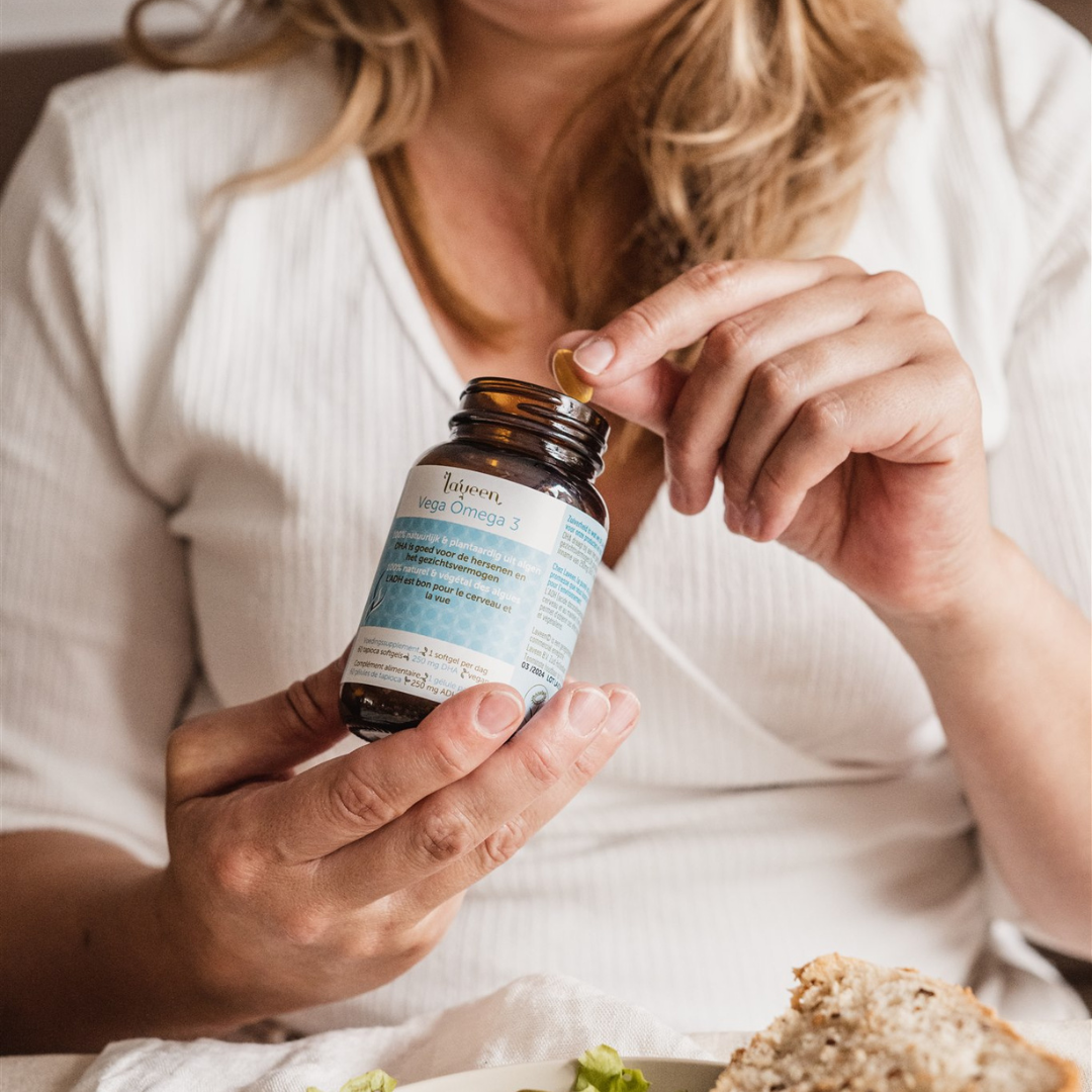 Sfeerfoto van de Vega Omega  3, een model neemt een softgel uit het potje.