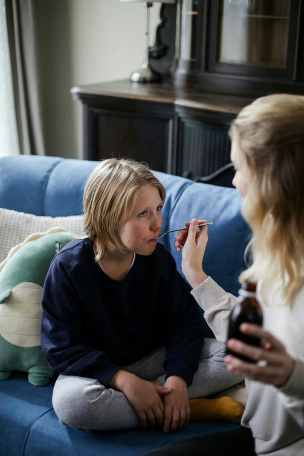 moeder geeft hoestdrank aan haar kind