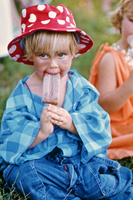 zonnesteek kind: een kind met een rood hoofd eet een ijsje