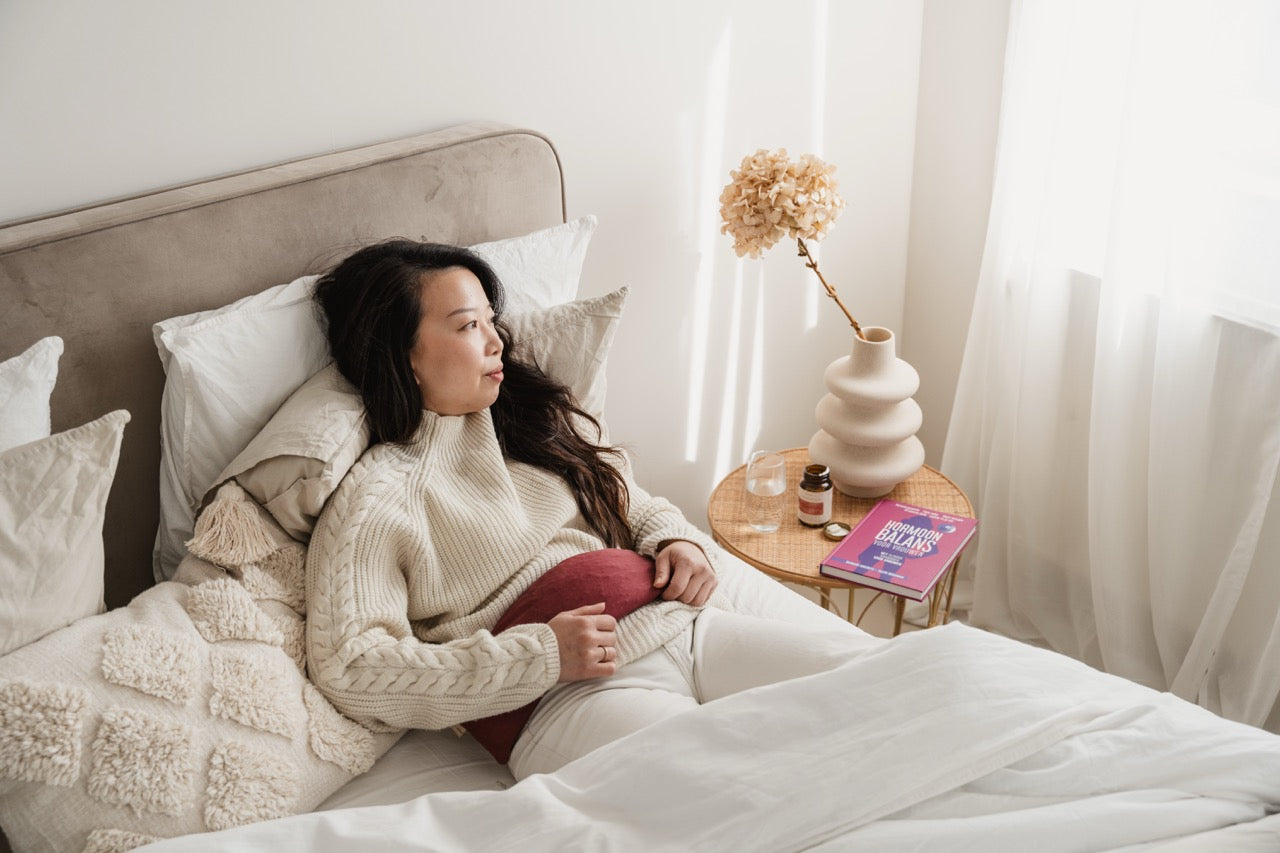 laag progesteron: vrouw op bed met een boek over hormonale balans