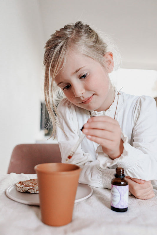 Kinderthee: meisje doet weerstand drops van Laveen in haar thee