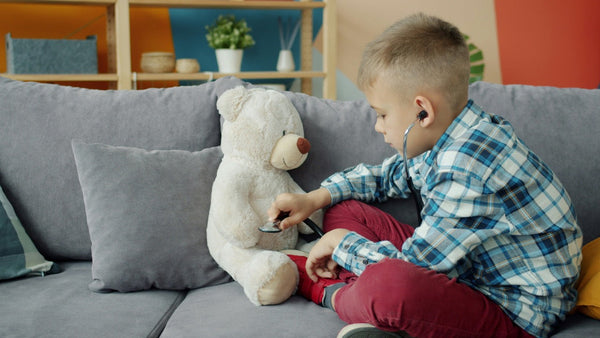 Buikpijn kind verzachten: een jongen speelt dokter met zijn teddybeer