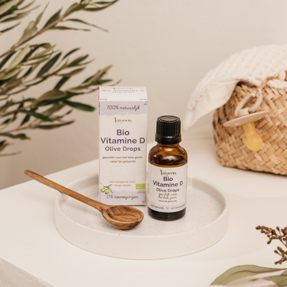 Flesje en verpakking van Laveen Bio Vitamine D druppels op een schaaltje met houten lepeltje. Geschikt voor het hele gezin vanaf de geboorte, met biologische olijfolie en zonder toevoegingen.