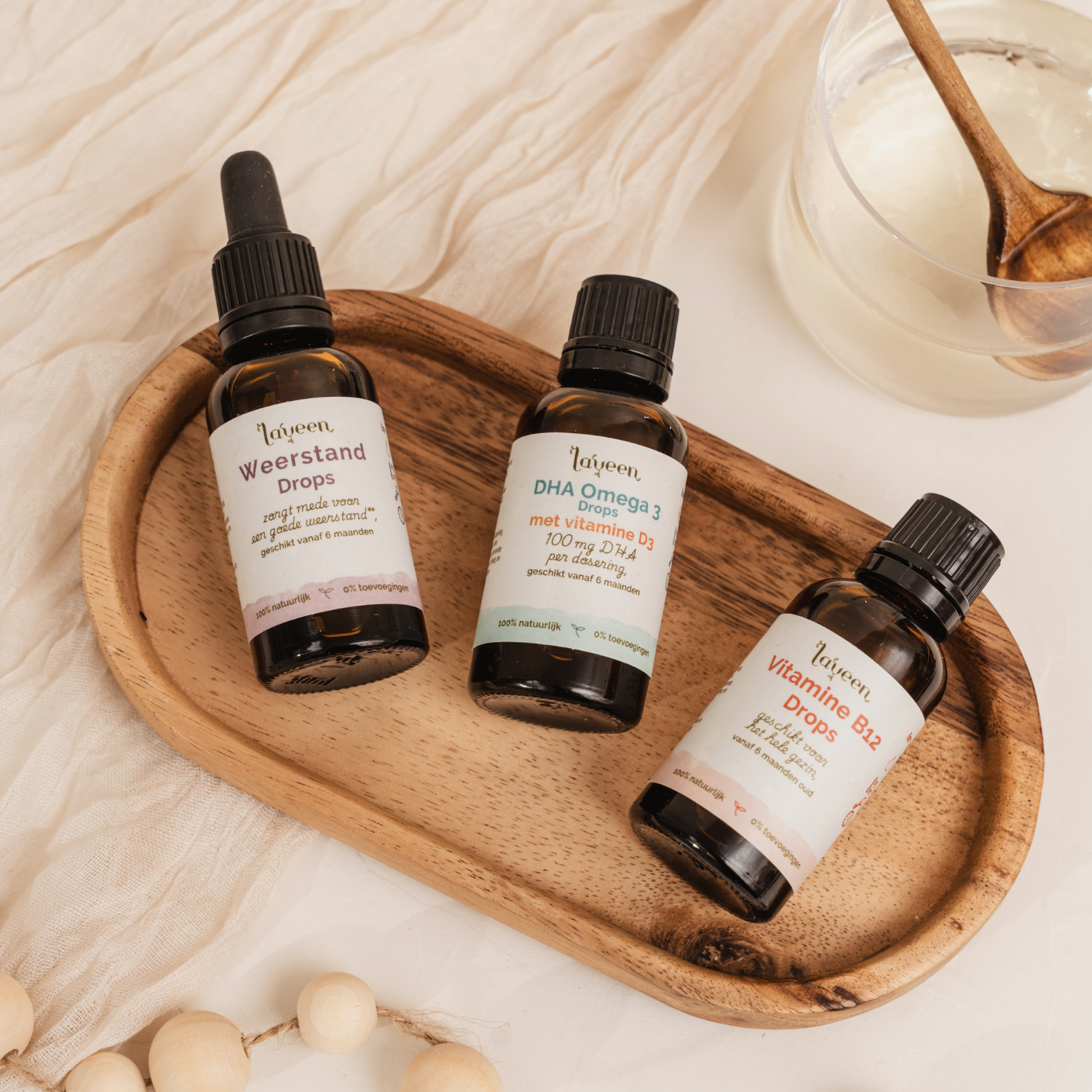 Sfeerfoto van de voordeelbundel Vega Kind Compleet van Laveen. Met de Weerstand Drops in een glazen pipetflesje, De DHA Omega 3 Drops en de Vitamine B12 drops, allebei in een glazen druppelflesje.